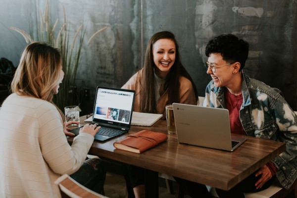 Group of 3 people working at a table with laptops